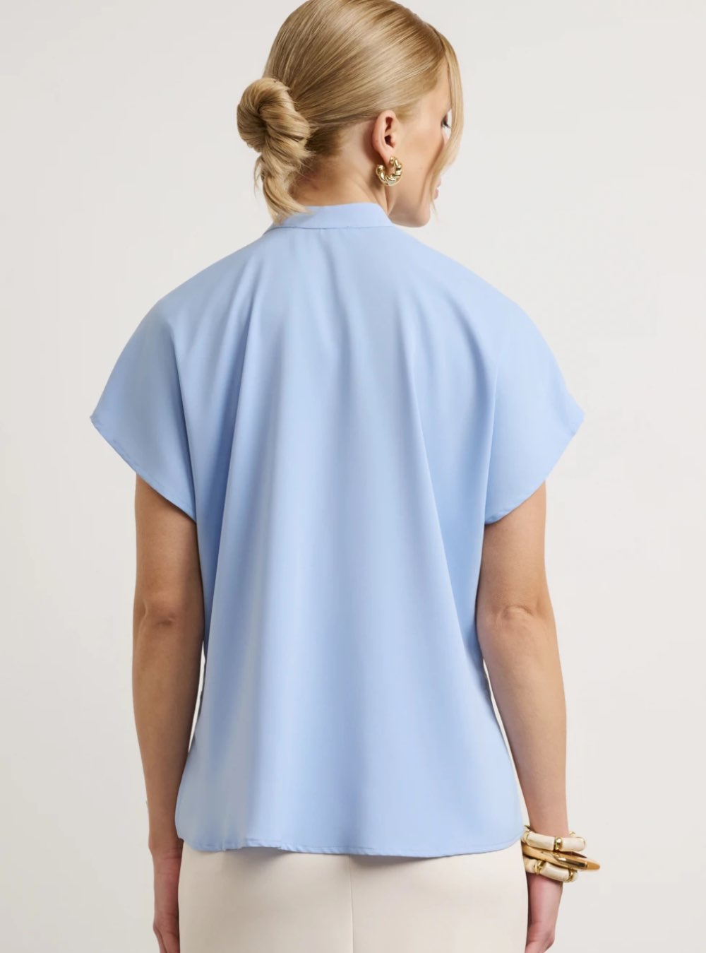 Γυναικείο πουκάμισο σχεδιασμένο με minimal αισθητική και ριχτή εφαρμογή. Διαθέτει μάο γιακά με διακριτικό διακοσμητικό κουμπί στο λαιμό. Κλείσιμο με κρυφά κουμπιά σε όλο το μήκος. Διαθέτει κοντό μανίκι. Το ύφασμα έχει απαλή υφή.