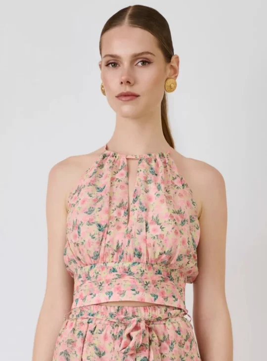 Ανάλαφρο floral crop top με halter λαιμόκοψη και ρομαντική αισθητική, ιδανικό για κομψές καλοκαιρινές εμφανίσεις. Διαθέτει αέρινη εφαρμογή στο μπούστο, cut-out λεπτομέρεια στο ντεκολτέ και φαρδιά μέση που αναδεικνύει τη σιλουέτα. Η σφηκοφωλιά στο πίσω μέρος προσφέρει άνετη εφαρμογή, ενώ το δέσιμο στον λαιμό ολοκληρώνει το θηλυκό design. Το floral print σε ροζ αποχρώσεις χαρίζει elegant και romantic χαρακτήρα, ιδανικό για resort looks, καλοκαιρινές εξόδους και ιδιαίτερες περιστάσεις. Συνδυάζεται υπέροχα με matching φούστα ή ψηλόμεσα bottoms.